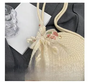 Close-up of beige woven round handbag with pink floral lace embroidery ribbon detail