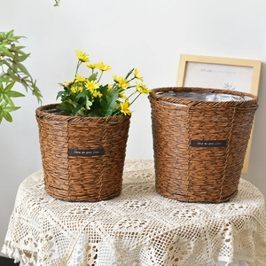 Close-up of woven straw plant pots with waterproof lining and leather label detail