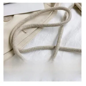 Détail de la bandoulière en corde de coton tissé crème sur un mini sac seau d'été