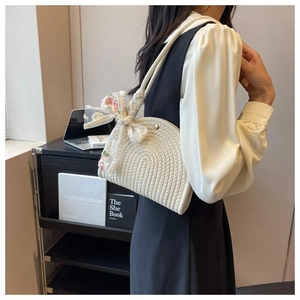 Close-up of white woven shoulder bag featuring lace bow and floral embroidery details