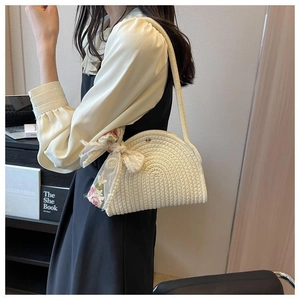 Detail of cream woven shoulder bag featuring pink floral lace bow and textured pattern