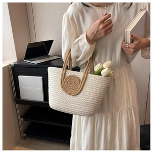Detailed view of the off-white woven tote bag texture and circular straw handle accent