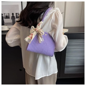 Detail of purple woven shoulder bag with floral chiffon bow accessory on white shirt
