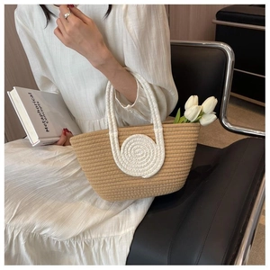 Close-up of handmade straw tote bag with white cotton rope spiral and floral accents