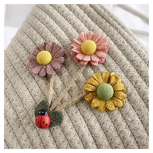 Détail du sac seau tissé main avec fleurs en tissu et décoration de coccinelle mignonne