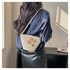 Détail du sac seau en paille tissé main avec décor floral et breloque coccinelle