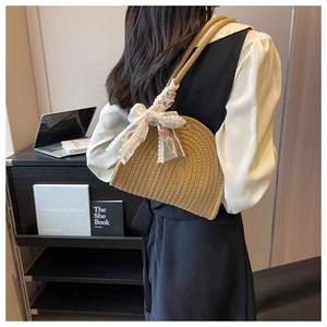 Detail of hand-woven straw shoulder bag with delicate white floral lace bow decoration