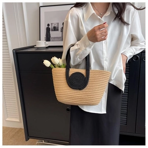 Detail of woven straw tote bag with black spiral handle and decorative white tulips