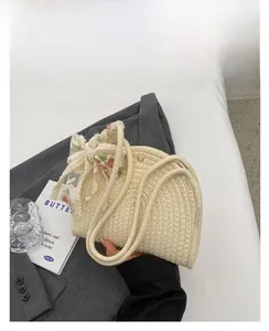 Close-up of cream woven handbag with delicate lace bow and natural cotton rope handle