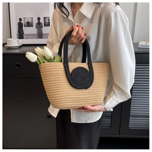 Detail of woven tote bag with wide black handles and decorative spiral circular patterns