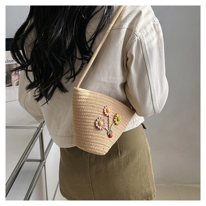 Détail d'un mini sac seau tissé beige avec broderie florale 3D et décor de coccinelle