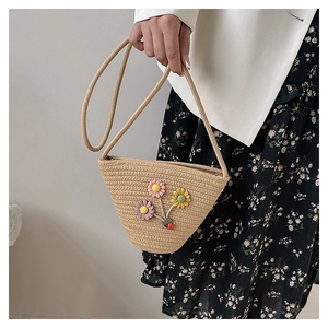 Détail d'un sac seau tressé avec des fleurs au crochet et fermeture éclair