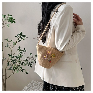 Détail du sac seau en paille tressée avec fleurs 3D sur une robe à fleurs