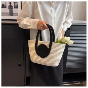 Close-up of minimalist woven tote bag with white cotton texture and black cord handles