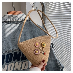 Vue détaillée du sac seau en paille tissée avec ornements floraux et décor de coccinelle