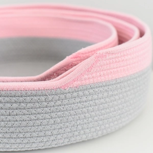 Gros plan sur la texture tressée en coton rose et gris du panier pour animaux