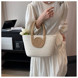 Close-up detail of a hand-woven tote bag in cream white with brown disk accents