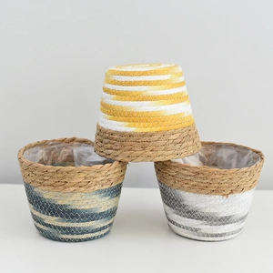 Detail of hand-woven grass planters with waterproof lining and colorful striped base design