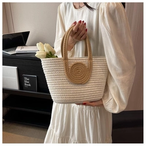 Detail of woven tote bag with round spiral patch held in a minimalist home setting