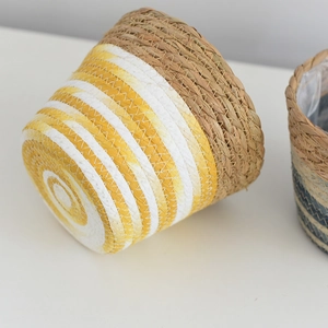 Detail of hand-woven straw flower pot showing yellow spiral texture and waterproof lining