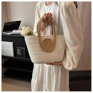 Detail shot of white woven tote bag with brown ring handle and fresh tulips inside