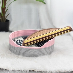 Détail d'un panier en corde de coton rose et gris tissé main sur un tapis blanc