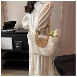 Detail of hand-woven tote bag with circular spiral patterns and brown handles