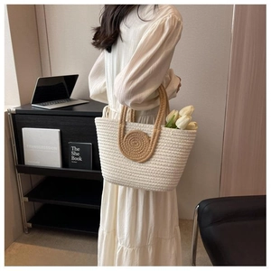 Detail of hand-woven tote bag with contrast cream body and brown circular handle