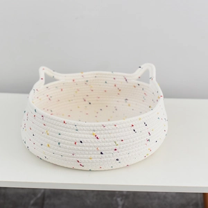 Close-up of woven white cotton rope cat bed with cat ear handles and colorful speckles
