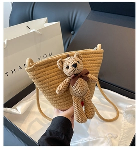 Détail du sac seau en paille tissé à la main avec ours en crochet et bandoulière longue