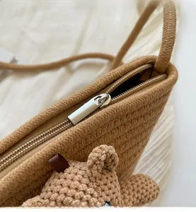 Détail de la fermeture éclair argentée et texture tissée sur un sac en paille kaki