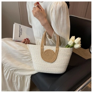Close-up of handmade cotton rope tote bag with brown handles and woven round patch
