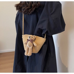 Détail d'un sac à bandoulière en paille tissée orné d'un adorable ours en peluche tricoté