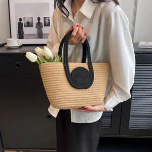 Minimalist woven straw tote bag with black handles and a rustic handmade texture