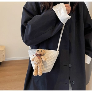 Détail du sac à bandoulière tissé crème avec un adorable pendentif ours en peluche doux