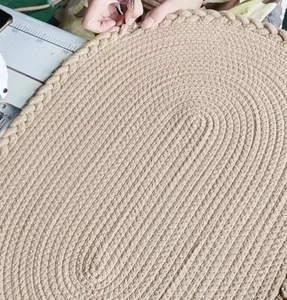 Détail d'un tapis ovale tissé main montrant la texture en spirale et le bord tressé