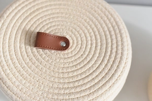 Detailed macro view of woven cotton rope lid with brown leather handle and silver rivet
