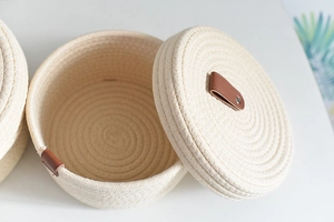 Close-up of woven cotton rope storage basket with brown leather handle and lid details