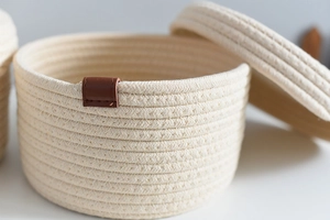 Detail of woven cotton rope storage basket with decorative leather tag and lid