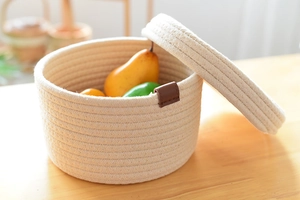 Detail of woven cotton rope storage basket with lid and brown leather buckle accent