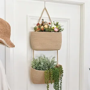 Detail of a two-tier woven hanging basket with artificial plants on a white door