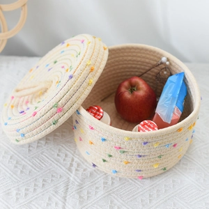 Detailed top view of a woven storage basket with colorful pom-poms and matching lid
