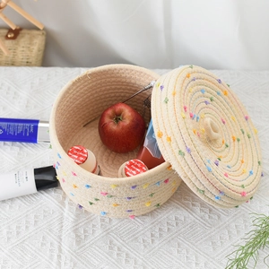 Detail of hand-woven cotton rope storage basket with lid and colorful pom-poms