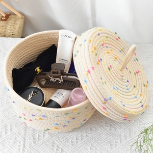 Detail view of woven storage basket with colorful pom poms and lid for desktop organizing