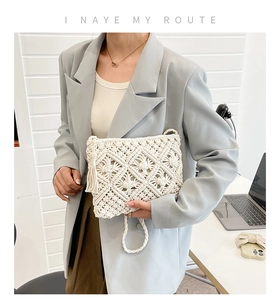 Détail du sac à main tissé en coton avec pompon à franges sur une tenue de blazer gris