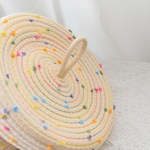 Close-up of woven cotton rope storage basket with colorful pompoms and top handle