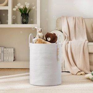 Detail of white cotton rope woven storage basket with dual handles and wood bead tassels