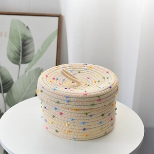 Detail of a white woven cotton rope storage basket featuring colorful polka dots and a lid