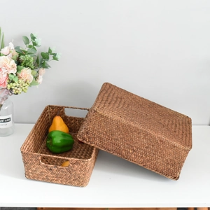 Detail of hand-woven wicker storage baskets with lids and handles on a clean white desk