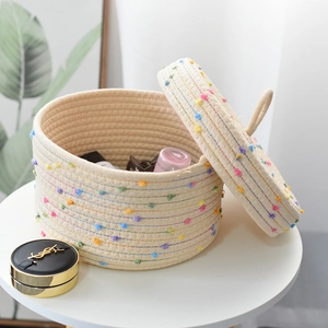 Close-up of cotton rope storage basket with colorful pompoms and lid for desktop storage